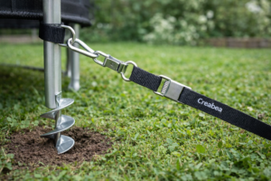 Creabea grondanker geplaatst in de grond voor het stevig verankeren van een trampoline in de tuin