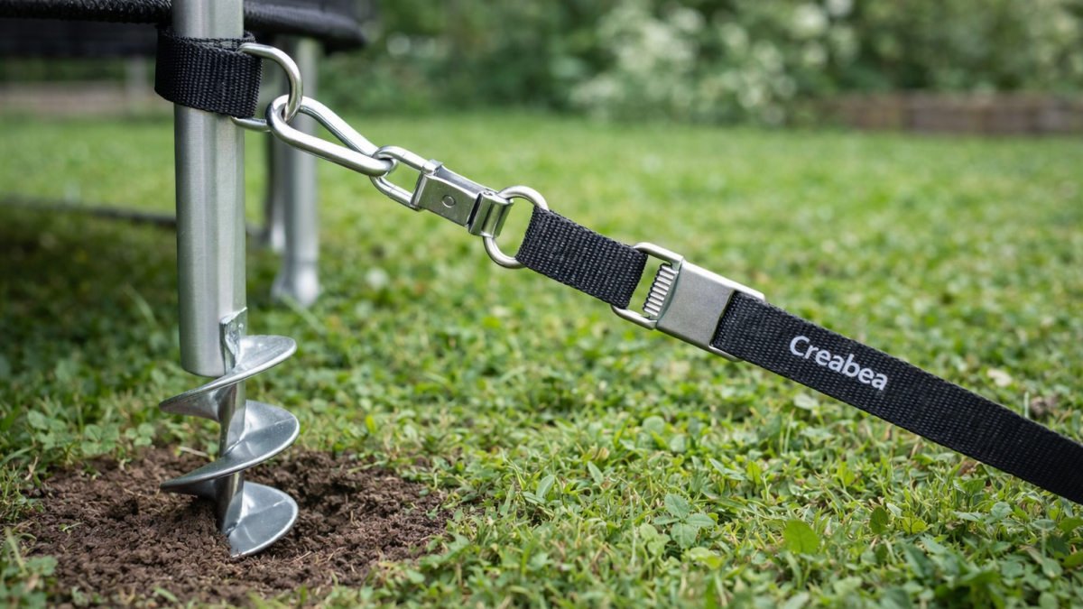 Creabea grondanker geplaatst in de grond voor het stevig verankeren van een trampoline in de tuin